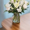 White floral bouquet in a clear glass vase on a wooden table