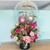 Pink rose arrangement with a clear balloon and metallic balloons in a black box