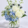 Blue hydrangeas and white roses in a clear glass vase