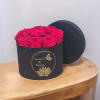 Pink roses in a black round gift box with a lid behind it
