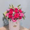 Pink roses and gerbera daisies arranged in a round hatbox
