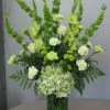 Green and white floral arrangement in a glass vase