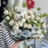 A luxurious and refined floral arrangement featuring pristine white orchids, soft ivory