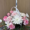 Pink and white mixed flowers arranged in a white basket. 
