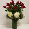 Tall arrangement of red roses and white hydrangeas in a clear green-lined glass vase