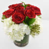 Compact arrangement of red roses and white hydrangeas in a glass cylinder vase