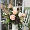 Peach and white roses with dried accents in a tall white ceramic vase