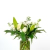 White lilies, roses, and other white flowers arranged in a clear glass jar vase