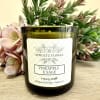 Green glass pineapple and sage candle with decorative foliage behind it