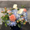Blue hydrangeas with pink roses and white calla lilies in a dark vase