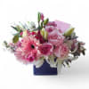 Low pink and white flower arrangement with roses, gerberas, and lilies in a blue glass cube vase