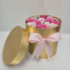 Round gold hatbox of pink and pale roses with lid and pink ribbon bow.