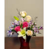 Mixed arrangement of pink and cream roses, lilies, and purple alstroemeria in a red vase