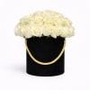 Round box of white roses in a black hatbox with a gold rope handle
