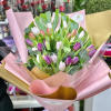 Hand-tied bouquet of pink, purple, and white tulips wrapped in pink and gold paper with a ribbon