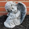 Small stone angel statue with folded wings resting its head on its arms