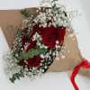Bouquet of red roses and white baby's breath wrapped in brown paper