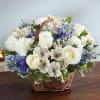 White and blue mixed flower basket arrangement on a wooden table