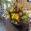 Basket arrangement of yellow and pink roses with yellow lilies and white snapdragons