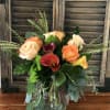 Vase arrangement of peach roses and red and yellow calla lilies in a clear glass vase