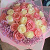 Round bouquet of pink and cream roses with lavender filler flowers wrapped in pink translucent paper