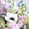 Pastel bouquet with white anemone, pink stock, and light blue delphinium flowers.