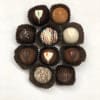 Assorted chocolate truffles with varied toppings arranged in a circle on a white background