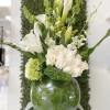 White and green flower arrangement with calla lilies and roses in a round glass vase