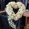 White floral heart-shaped funeral wreath with cascading orchids