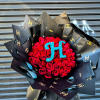 Large bouquet of red roses with blue monogram, wrapped in black logo paper