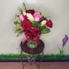 Mixed bouquet of red and pink roses with white lilies in a clear glass vase with a red bow.