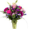 Tall mixed bouquet of pink roses and snapdragons with purple blooms in a clear glass vase