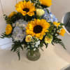 Bouquet of sunflowers, hydrangeas, and small white flowers in a glass vase
