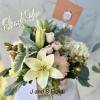 Bouquet of pale lilies and blush roses with a thank-you topper