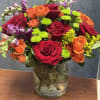 Mixed bouquet of red, orange, and purple flowers in a glass vase