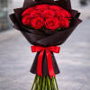 Bouquet of red roses wrapped in dark paper with a red satin bow