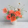 Peach roses and poppy-style blooms with white daisies in a small white ceramic vase