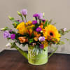 A colorful hammered watering can with an assortment of seasonal blossoms with