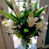 Tall bouquet of white lilies and small white flowers in a glass vase