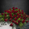 A beautiful casket piece filled with red roses filled with greenery.