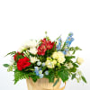 Red, white, yellow, and blue mixed flower basket arrangement in a light wood handled basket