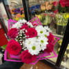 Hand-tied bouquet of hot pink roses, white daisies, and baby's breath in bright pink wrap