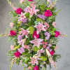 Tall pink and green standing spray with lilies and roses on a metal easel