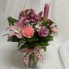 Mixed pink and purple flower arrangement in a clear vase with a polka dot bow