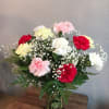 Mixed red, pink, white, and yellow carnations with baby's breath in a clear glass vase