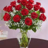 Arrangement of red roses with white filler flowers in a clear glass vase on a table
