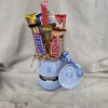 Light blue Hydro Flask mug filled with assorted candy bars and curly ribbon, with matching lid beside it.