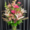 Tall pink and white lily and carnation arrangement with snapdragons in a clear glass vase