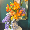 Bright orange lilies, tulips, chrysanthemum, and purple hyacinths in a blue and white ceramic vase