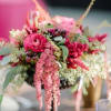 Low compote arrangement of pink and red flowers with trailing blooms and textured filler